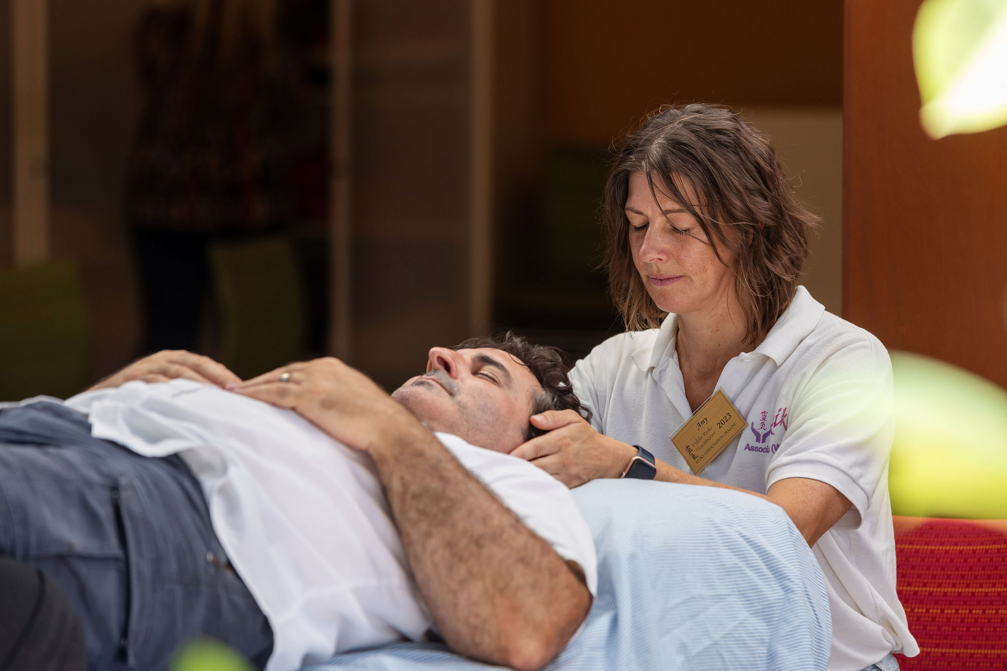 Amy giving a man Reiki, hand on head with eyes closed