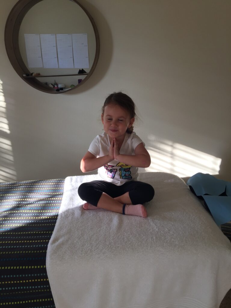 3 year old child in Gasso - this is a crossed legged reiki position with hands folded infront of chest.