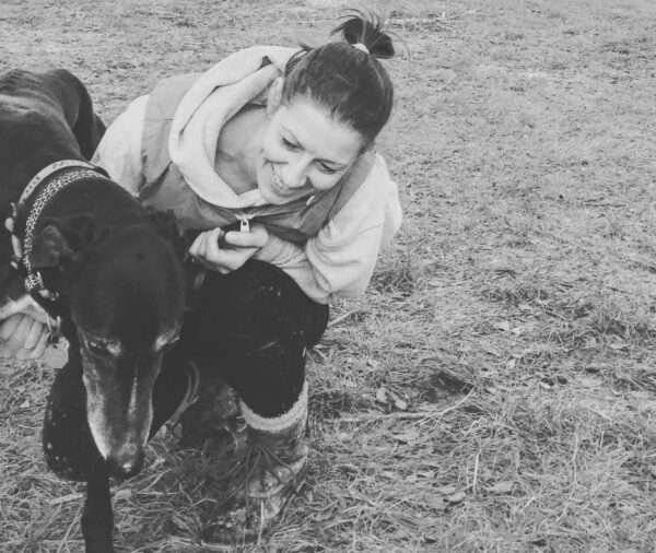 Black and white photo of Amy giving a greyhound Animal Reiki