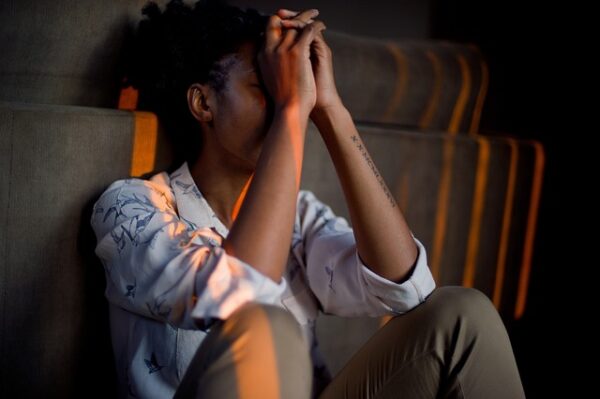 Upset woman with hands together held up to face