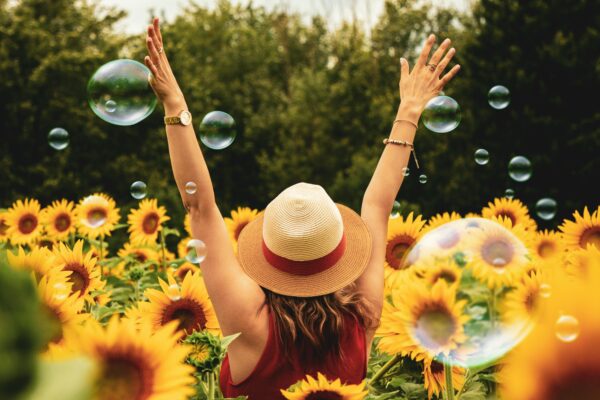 Elated woman in field of sunflowers and bubbles