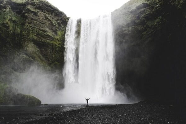 Exuberant person standing infant of a big waterfall