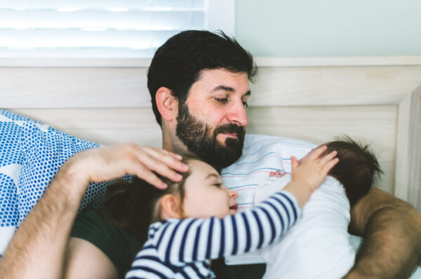 Proud father enjoys quality time at home with newborn baby and toddler daughter