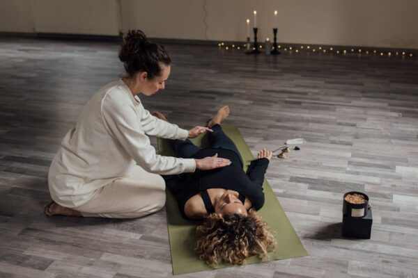 Woman giving hands-on Reiki to another woman lying on a mat during a group Reiki session in Beaconsfield WA